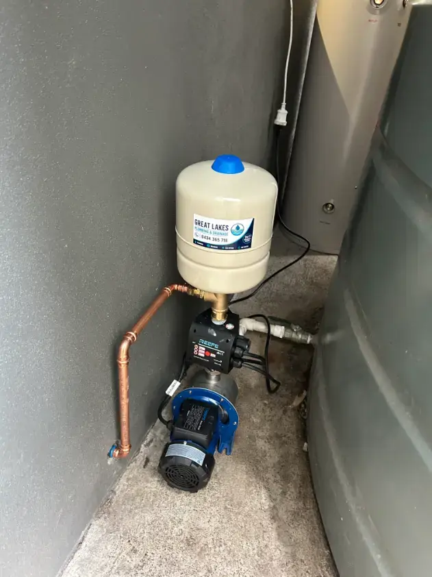 Water pressure pump and pressure tank installed beside a wall